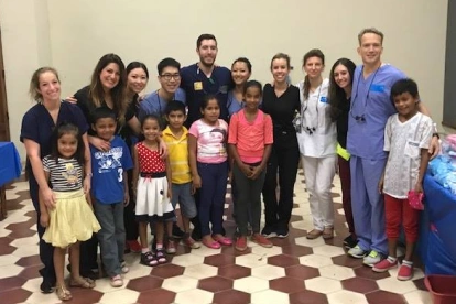 Dr. Peracchia and dental staff pose with diverse group of children in clinical setting.