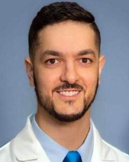 Professional headshot of Dr. Robert Peracchia wearing white lab coat and blue tie against blue background.