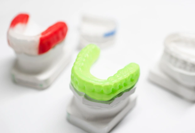 Colorful custom dental mouthguards and retainers displayed on white stands in a dental office setting.