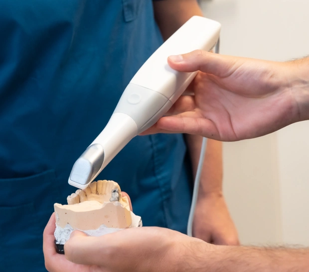 Dentist demonstrating dental scanner on model teeth during pediatric dental examination.