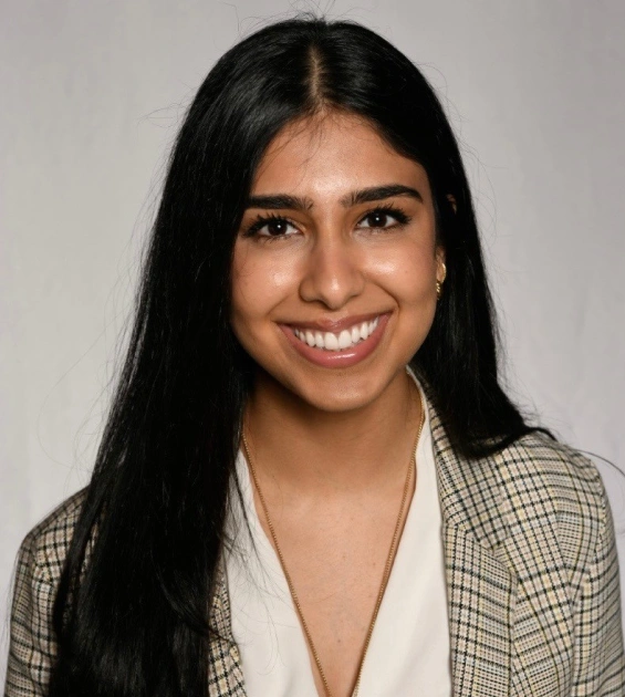 Young woman smiling at camera in professional headshot wearing plaid blazer and white top.